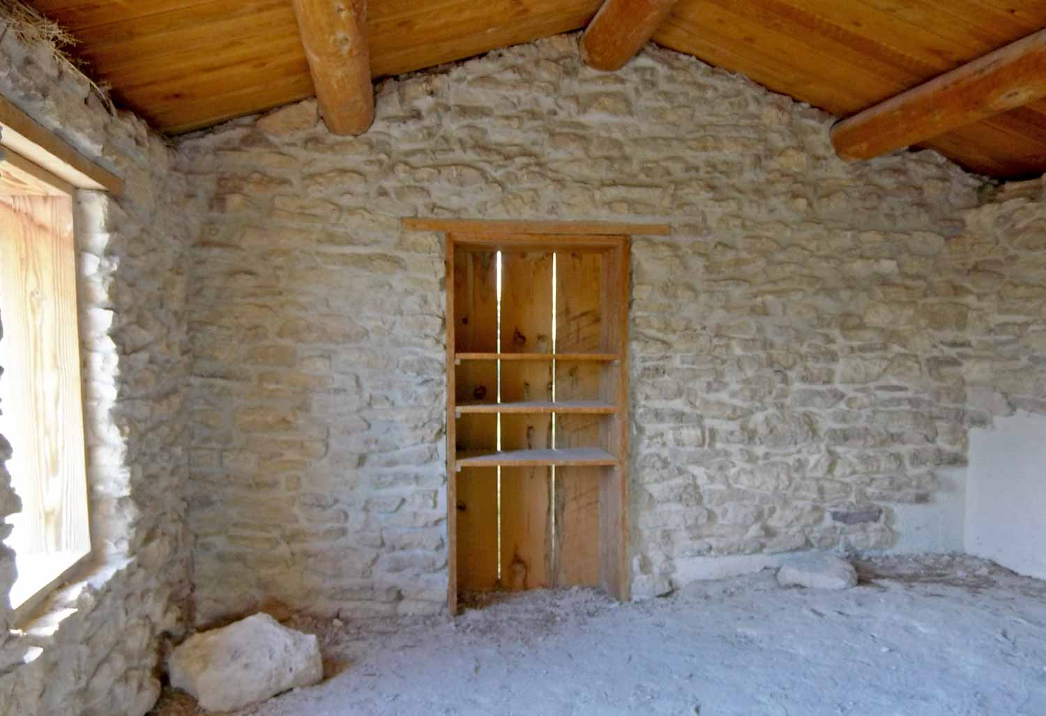 View inside the Longstreet cabin, a blank wall with a cut out wooden cupboard area.