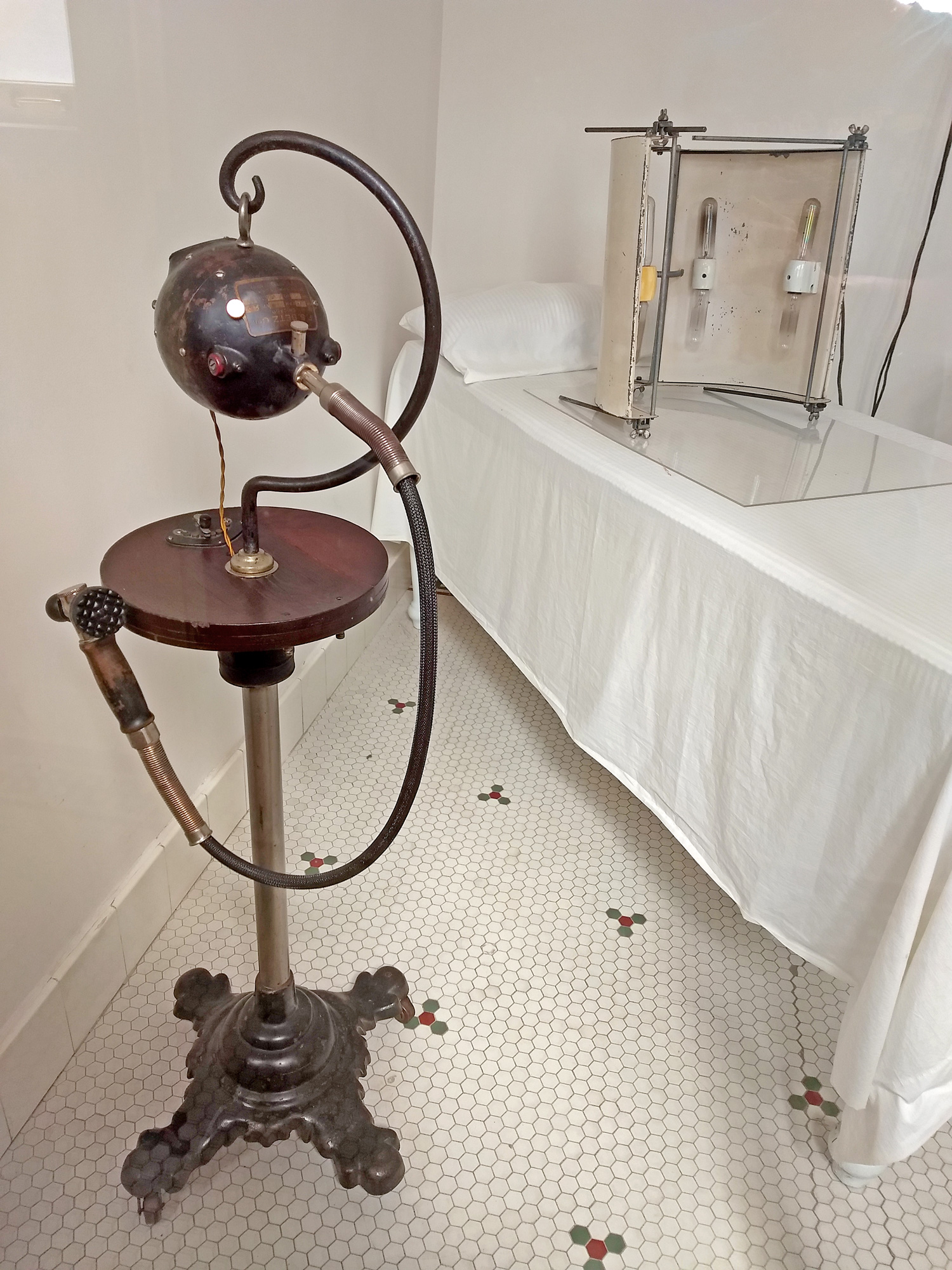 A large shiny globe with hoses on a stand, attachments on a single bed.